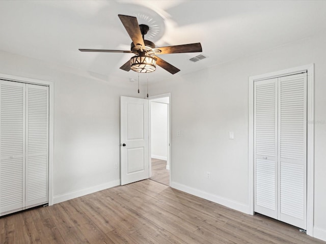 unfurnished bedroom with ceiling fan, visible vents, baseboards, and wood finished floors