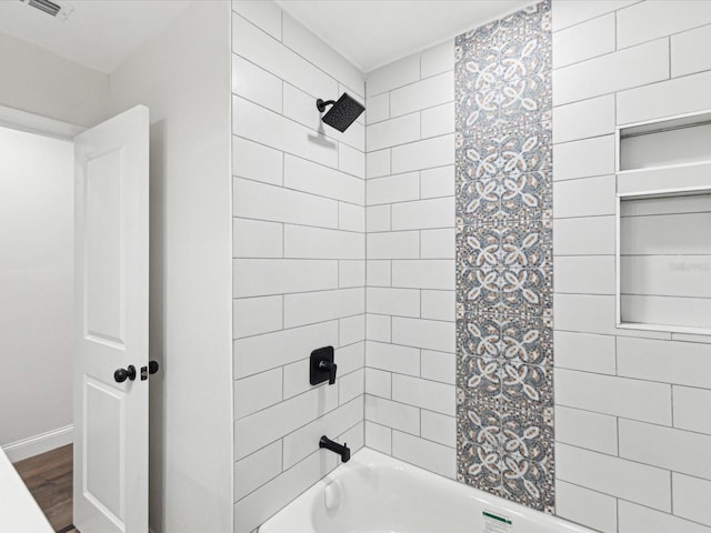 bathroom with visible vents, baseboards, shower / washtub combination, and wood finished floors