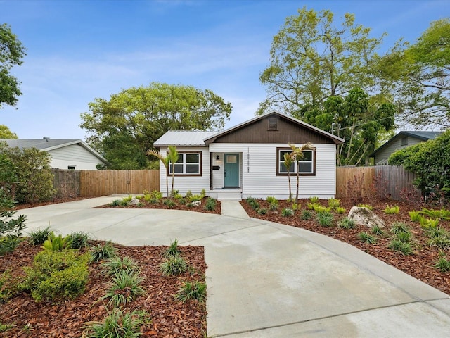 ranch-style house featuring metal roof and fence