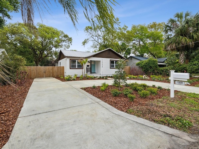 ranch-style home featuring metal roof, concrete driveway, and fence