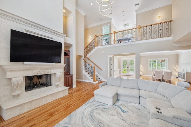 living area featuring crown molding, a premium fireplace, wood finished floors, baseboards, and stairs