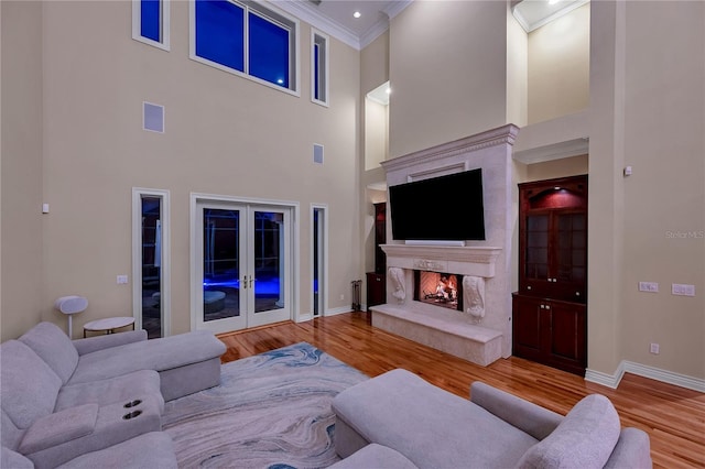 living area with a premium fireplace, ornamental molding, wood finished floors, and french doors