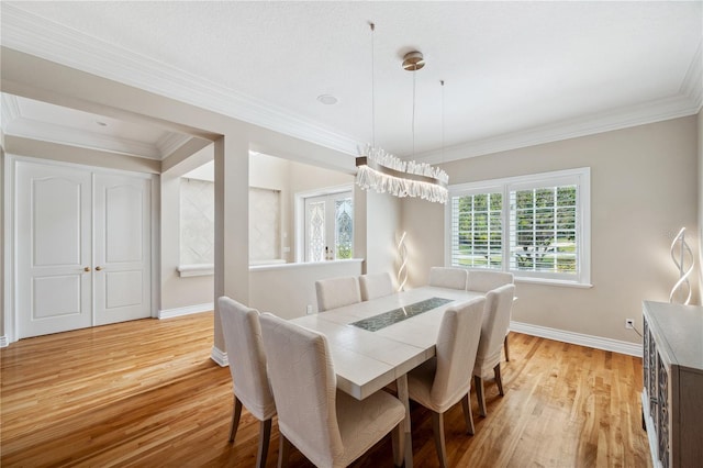 dining room with light wood-style flooring, ornamental molding, and baseboards