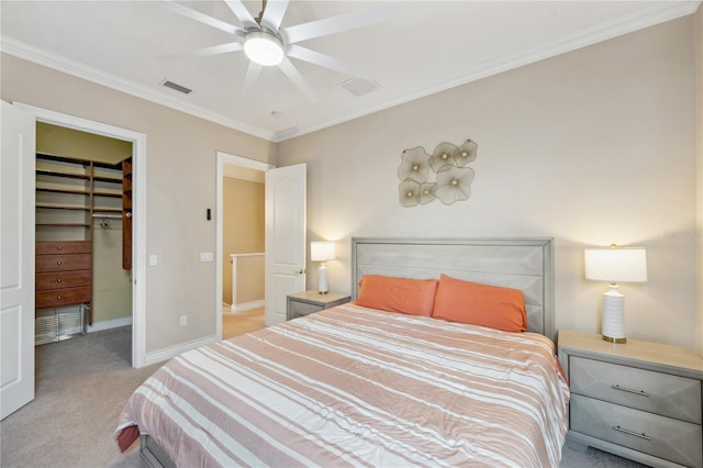 bedroom with carpet floors, a walk in closet, crown molding, visible vents, and baseboards