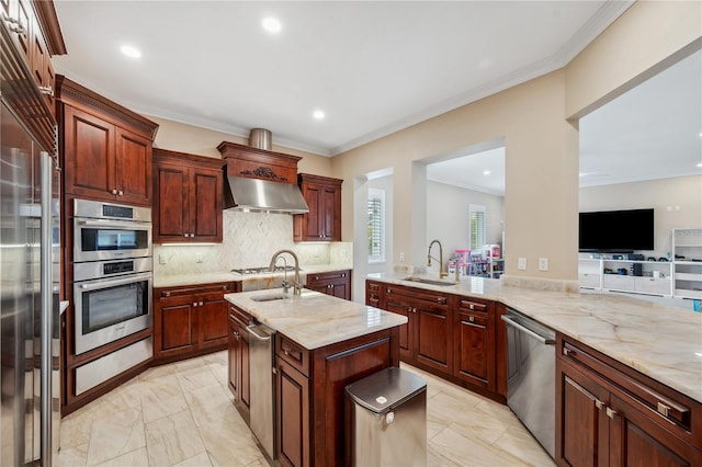 kitchen with a center island with sink, decorative backsplash, appliances with stainless steel finishes, range hood, and a sink