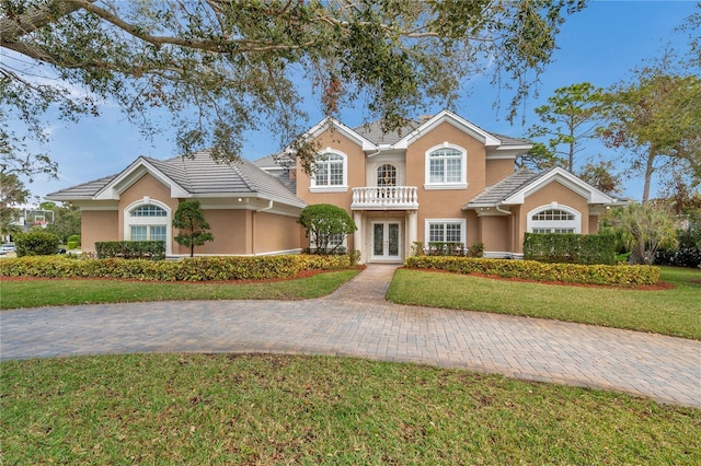 view of front of house featuring french doors, a front yard, a tile roof, and stucco siding