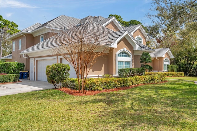 view of front facade with a garage, driveway, a tiled roof, stucco siding, and a front yard