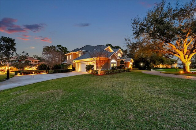 view of front of property with a garage, concrete driveway, a yard, and stucco siding