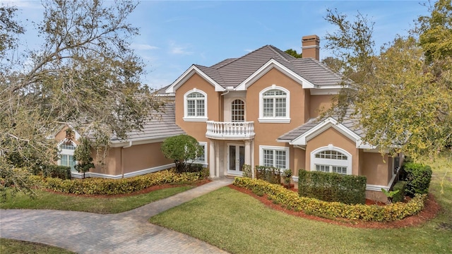 view of front of property featuring a chimney, french doors, a tiled roof, and stucco siding