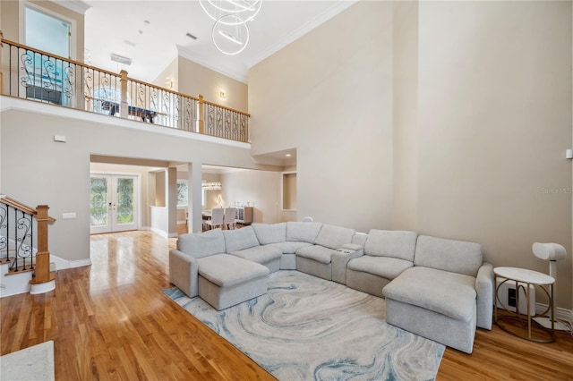 living room featuring wood finished floors, baseboards, stairs, french doors, and crown molding