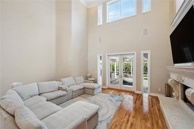 living room with visible vents, baseboards, french doors, light wood-style floors, and a high end fireplace