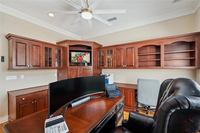 home office featuring visible vents, a ceiling fan, built in study area, ornamental molding, and light wood-type flooring