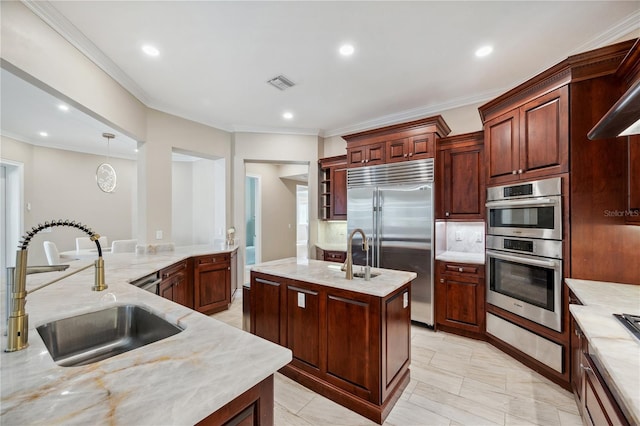 kitchen featuring a sink, visible vents, appliances with stainless steel finishes, light stone countertops, and an island with sink