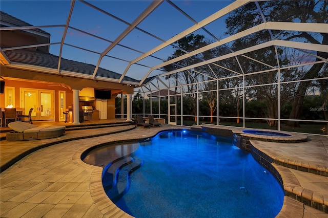 view of pool with a pool with connected hot tub, glass enclosure, and a patio