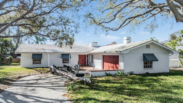 view of front of home featuring fence, stucco siding, a front lawn, a chimney, and a patio area