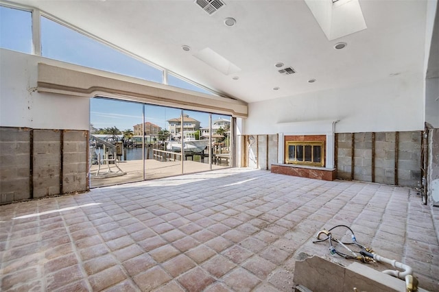 interior space with a high end fireplace, a skylight, visible vents, and high vaulted ceiling