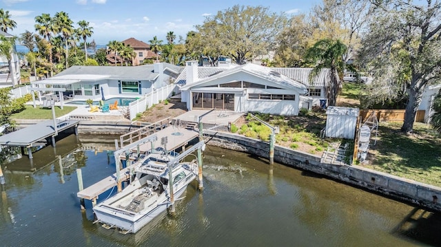 rear view of house with a patio area, a water view, boat lift, and fence