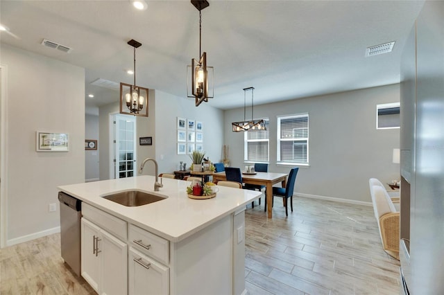 kitchen featuring an island with sink, light wood-type flooring, visible vents, and a sink