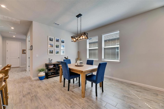 dining area featuring light wood-type flooring, visible vents, and baseboards