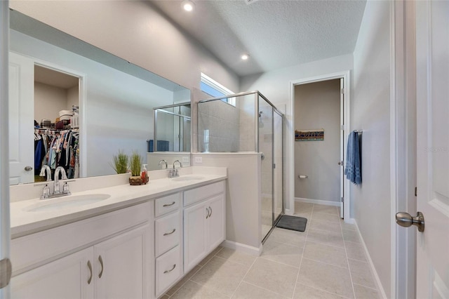 full bath with double vanity, a sink, a walk in closet, and a shower stall