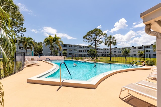 community pool with a patio area and fence