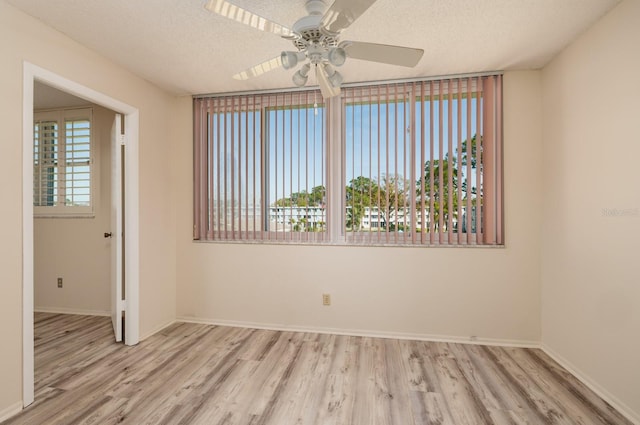 spare room featuring a healthy amount of sunlight, a textured ceiling, and wood finished floors