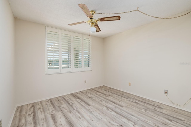 spare room featuring ceiling fan, a textured ceiling, wood finished floors, and baseboards