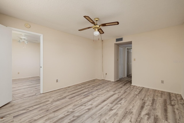 empty room with a ceiling fan, visible vents, light wood-style floors, and a textured ceiling