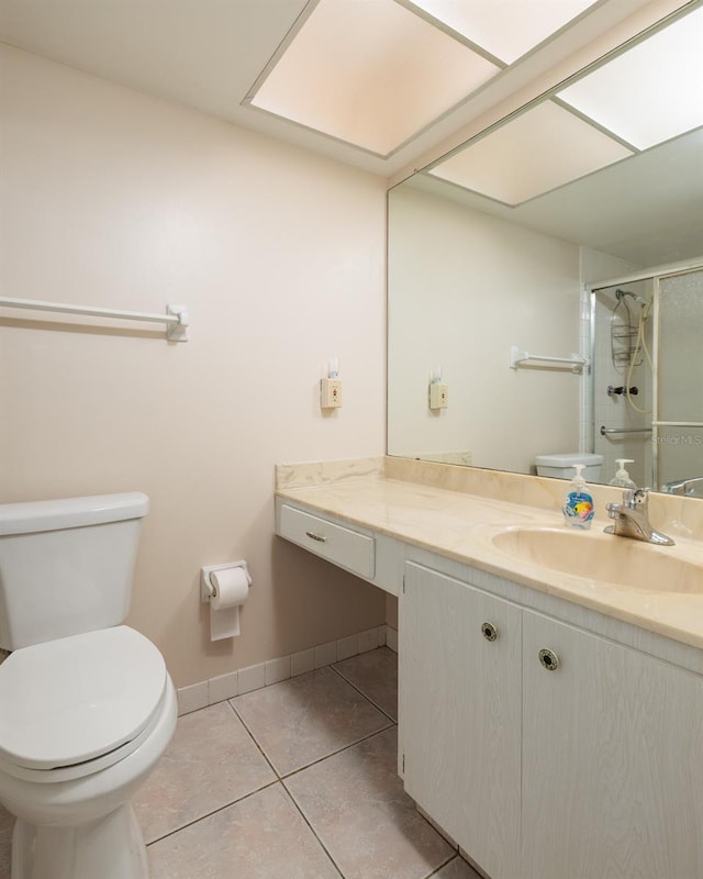 bathroom with tile patterned flooring, toilet, vanity, baseboards, and a stall shower