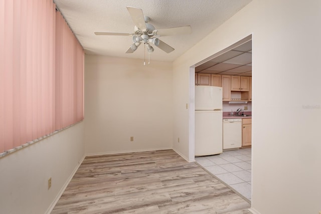 empty room with light wood-style flooring, a ceiling fan, a sink, a textured ceiling, and baseboards