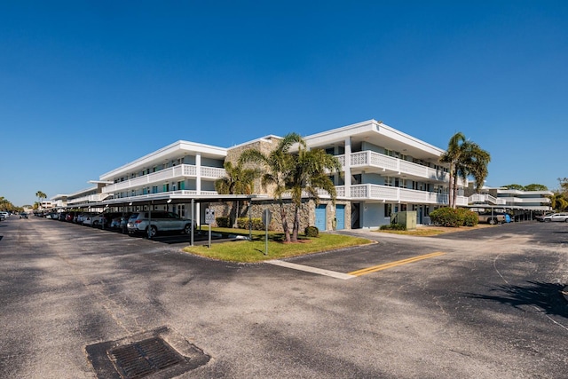 view of building exterior featuring covered and uncovered parking