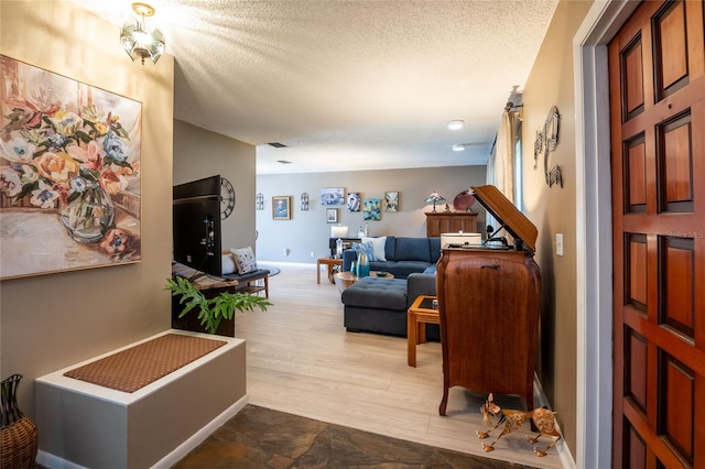 interior space with a textured ceiling, baseboards, and wood finished floors