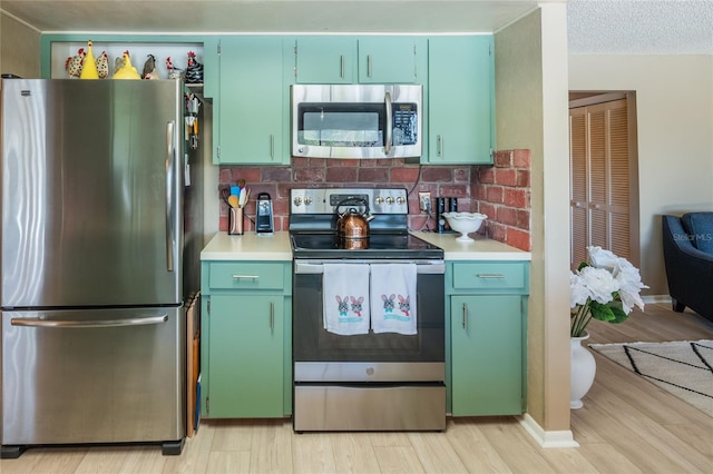 kitchen featuring a textured ceiling, light wood-style floors, appliances with stainless steel finishes, and light countertops