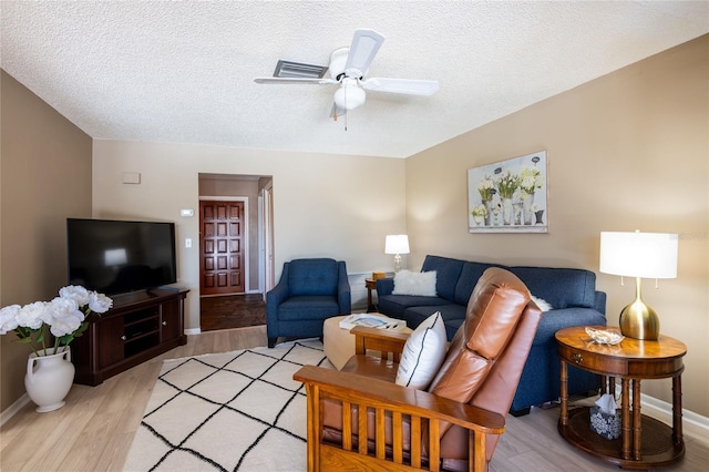 living room with baseboards, light wood-style floors, a ceiling fan, and a textured ceiling