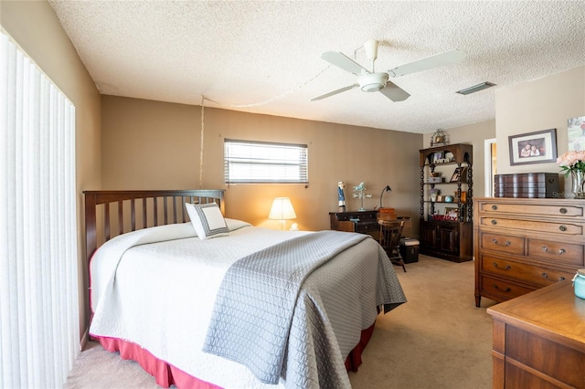 bedroom with visible vents, light carpet, a textured ceiling, and ceiling fan