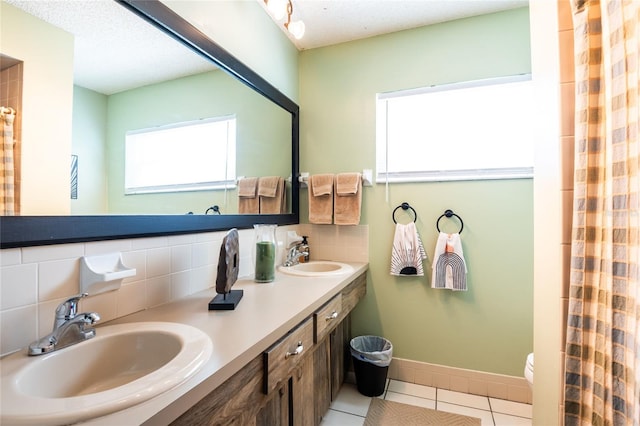 full bathroom featuring tile patterned floors, decorative backsplash, baseboards, and a sink