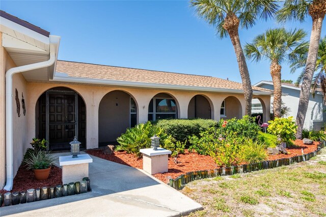 exterior space with roof with shingles and stucco siding