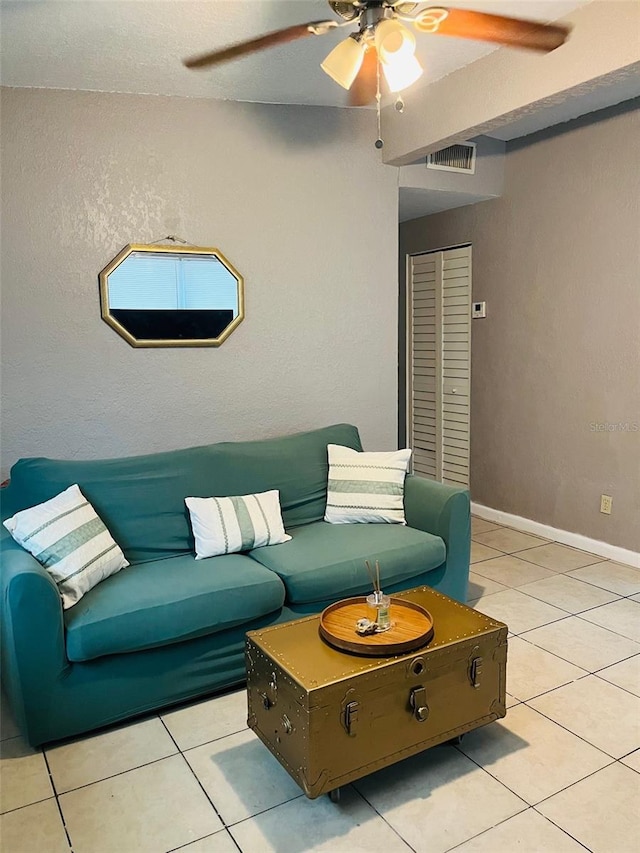 living room featuring light tile patterned floors, visible vents, baseboards, and ceiling fan