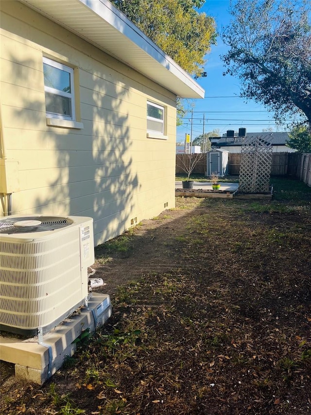 view of property exterior with a fenced backyard, concrete block siding, cooling unit, and an outdoor structure