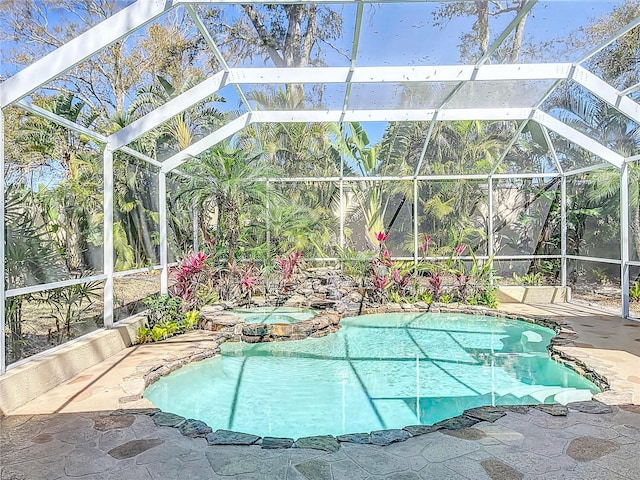 view of pool with a lanai, a pool with connected hot tub, and a patio