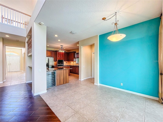 kitchen with wine cooler, pendant lighting, stainless steel fridge with ice dispenser, a textured ceiling, and baseboards