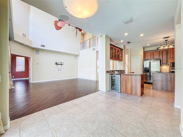 kitchen featuring open floor plan, visible vents, stainless steel refrigerator with ice dispenser, and light tile patterned floors