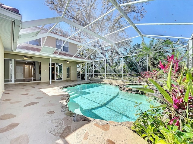 view of pool with a ceiling fan, a pool with connected hot tub, glass enclosure, and a patio