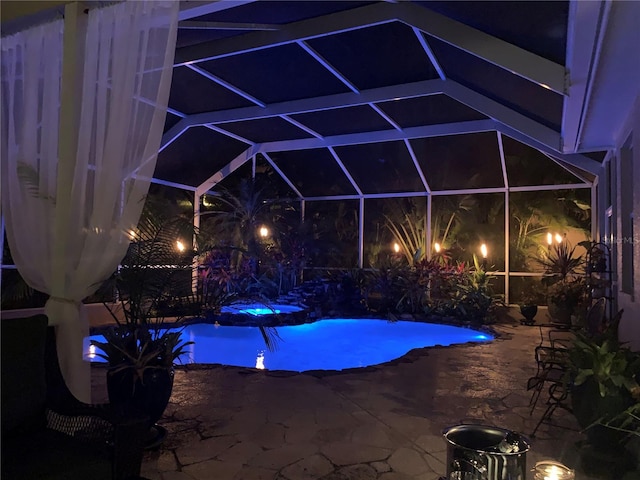 pool at night with a patio area, a lanai, and an outdoor pool