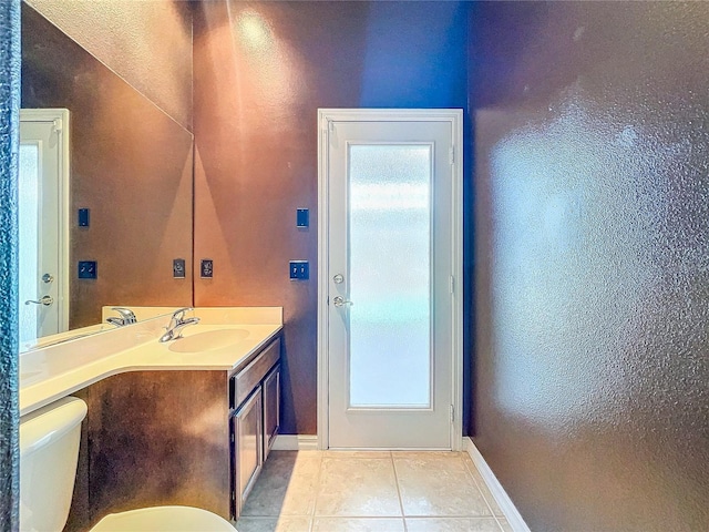 bathroom with baseboards, vanity, toilet, and tile patterned floors