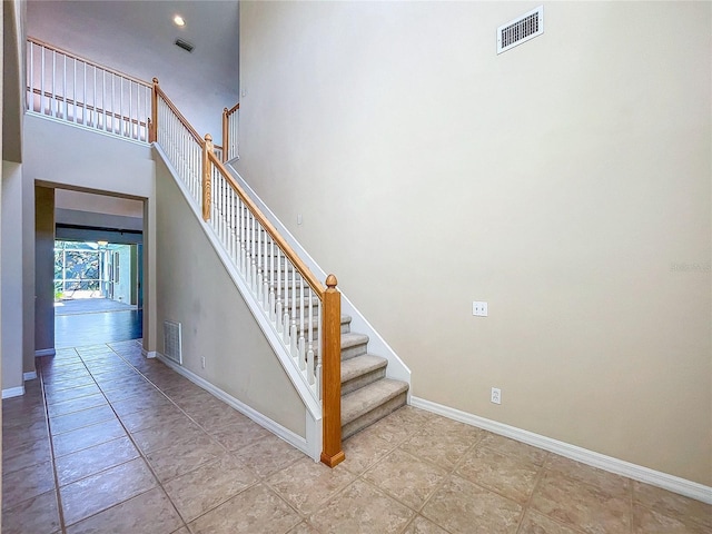 stairs with baseboards, a high ceiling, and visible vents