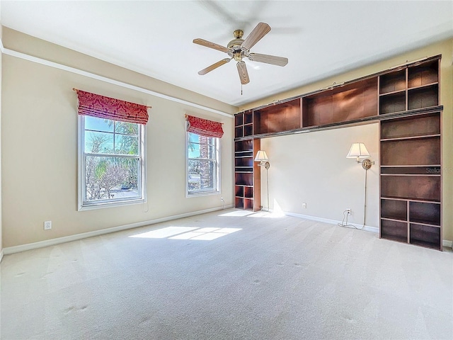 carpeted empty room featuring a ceiling fan and baseboards