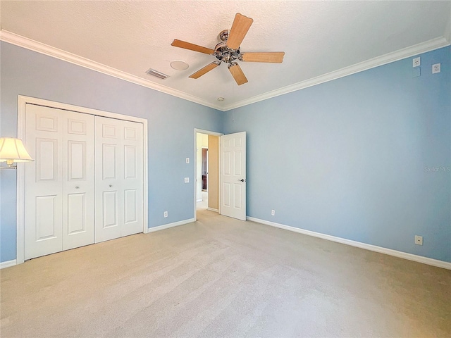 unfurnished bedroom with light carpet, baseboards, visible vents, ornamental molding, and a closet