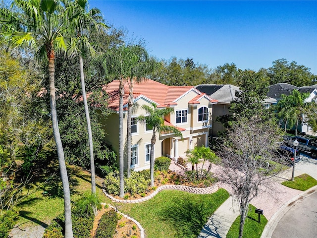 mediterranean / spanish house featuring a tile roof, driveway, and stucco siding