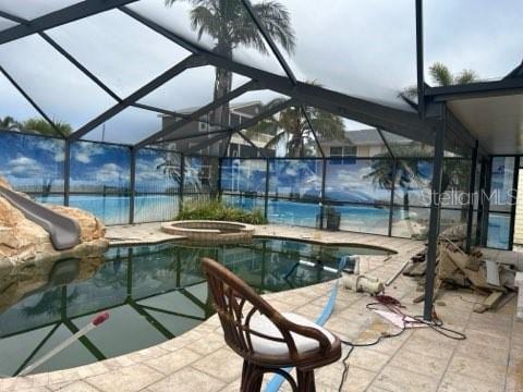 view of pool featuring a patio area, a pool with connected hot tub, glass enclosure, and a water slide